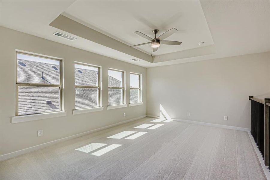 Unfurnished living room with a raised ceiling, light carpet, and a ceiling fan
