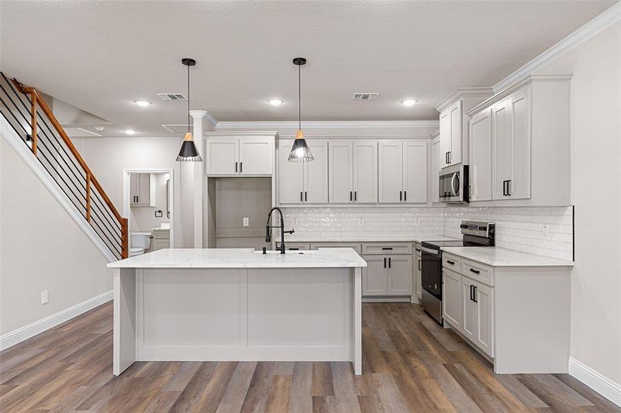 Kitchen featuring sink, decorative backsplash, hardwood / wood-style floors, and stainless steel appliances