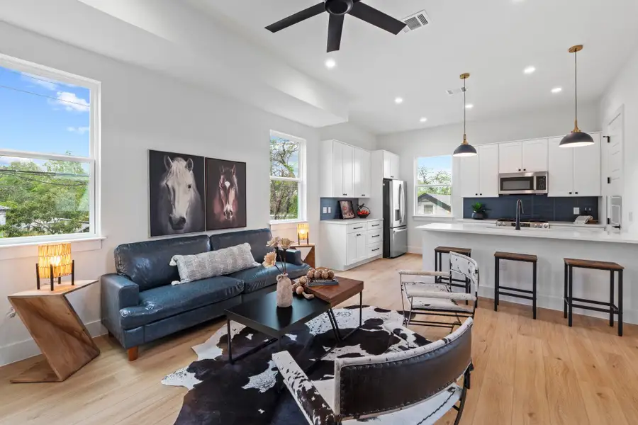 Crisp white walls and warm wood flooring frame an inviting, sunlit open concept living space.