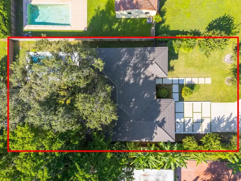 Aerial view showcasing the private pool, paver walkway, and lush, mature landscaping surrounding the home