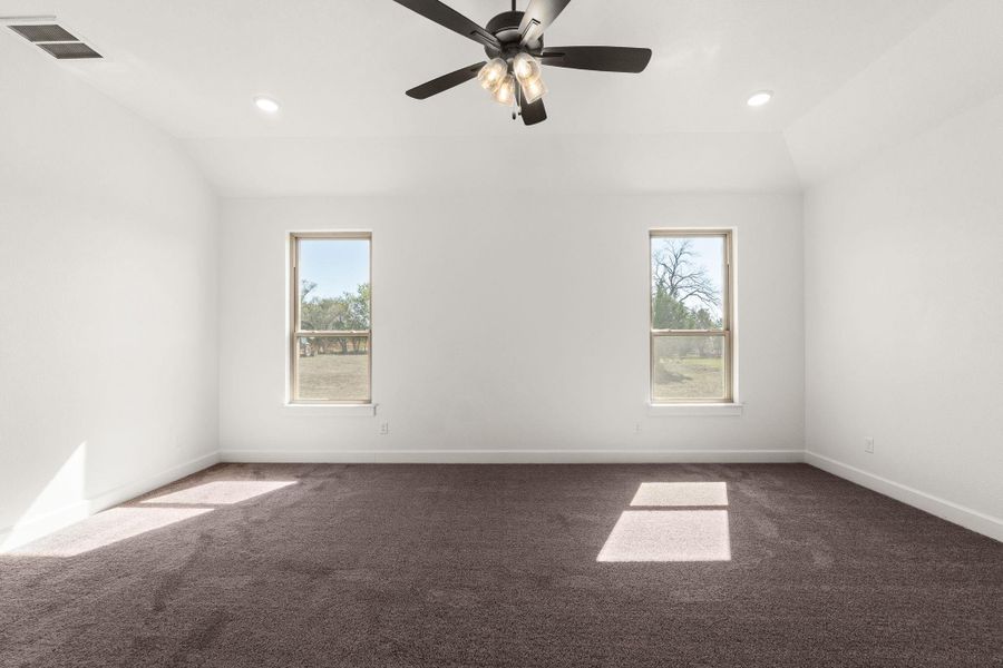 Spare room with dark carpet, plenty of natural light, recessed lighting, vaulted ceiling, and a ceiling fan