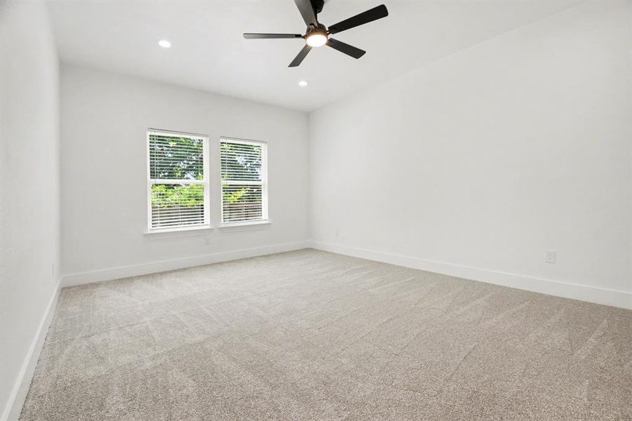 This inviting room features two windows with blinds, a modern ceiling fan, recessed lighting, and light-colored carpeting