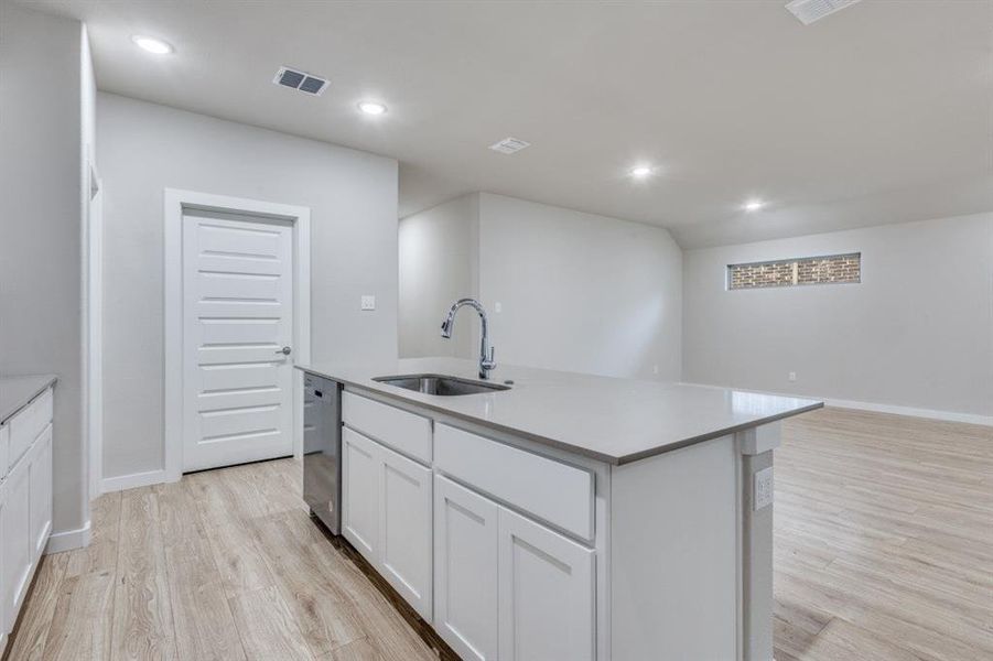 Kitchen with white cabinets, light wood-type flooring, recessed lighting, a kitchen island with sink, and open floor plan Kitchen with white cabinets, light wood-type flooring, recessed lighting, a kitchen island with sink, and open floor plan