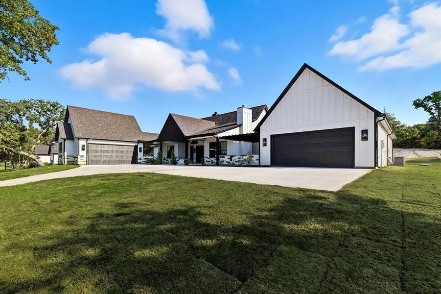 Modern inspired farmhouse featuring board and batten siding, a front lawn, driveway, and a garage Modern inspired farmhouse featuring board and batten siding, a front lawn, driveway, and a garage
