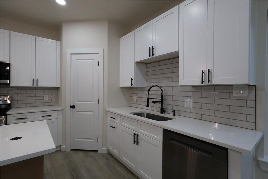 Kitchen featuring stainless steel appliances, white cabinets, light stone counters, light wood finished floors, and recessed lighting
