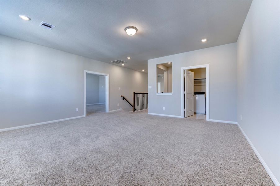 Spacious upstairs game room with open layout, plush carpet, and versatile space for entertainment or relaxation.