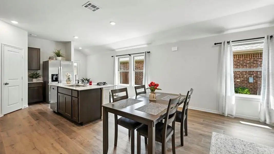 Open-concept living area featuring wood-finish flooring, recessed lighting, white walls, dark wood cabinetry, and an island with a light-colored countertop