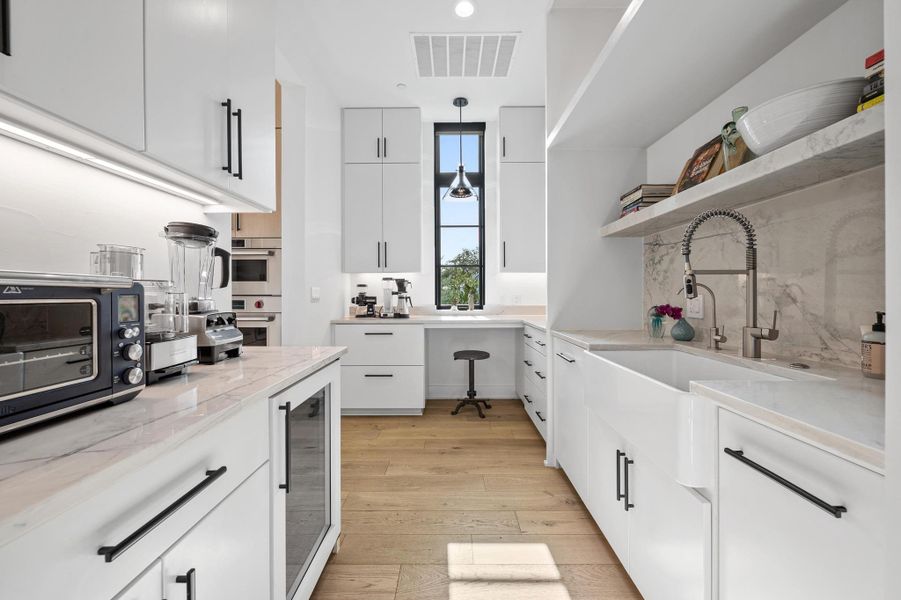 Kitchen with light wood-style flooring, visible vents, a sink, open shelves, and beverage cooler Kitchen with light wood-style flooring, visible vents, a sink, open shelves, and beverage cooler
