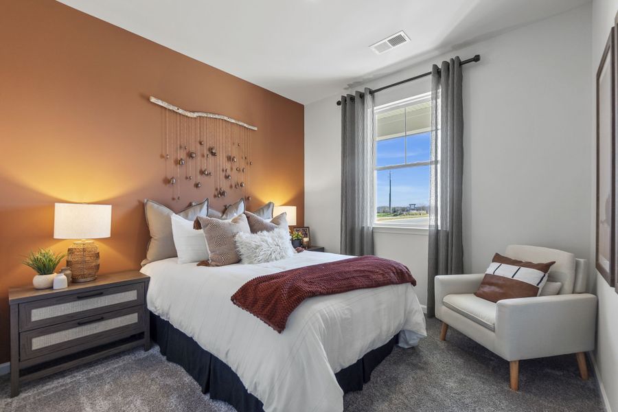 A bedroom with a bed and a chair.