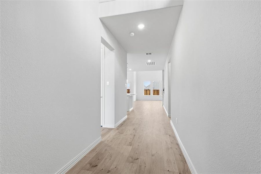 Hallway featuring a textured wall, light wood finished floors, and recessed lighting Hallway featuring a textured wall, light wood finished floors, and recessed lighting