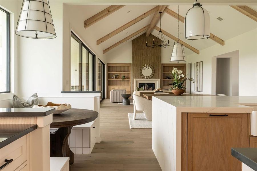 Kitchen featuring high vaulted ceiling, a large fireplace, decorative light fixtures, a chandelier, and open floor plan Kitchen featuring high vaulted ceiling, a large fireplace, decorative light fixtures, a chandelier, and open floor plan