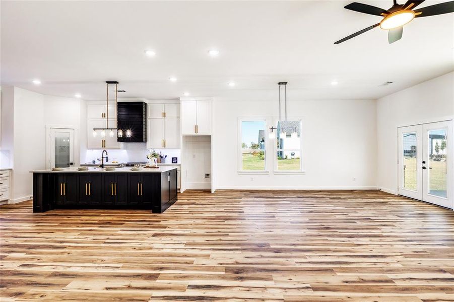 Kitchen featuring dark cabinetry, open floor plan, white cabinetry, plenty of natural light, and recessed lighting