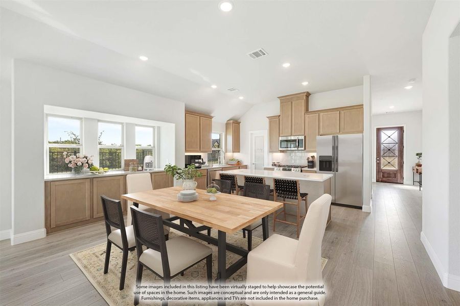 Open dining and kitchen area with light wood cabinets, center island, stainless appliances, and hardwood floors