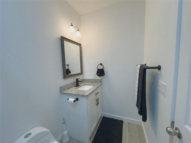 Hallway Bathroom featuring tile floors, toilet, and vanity