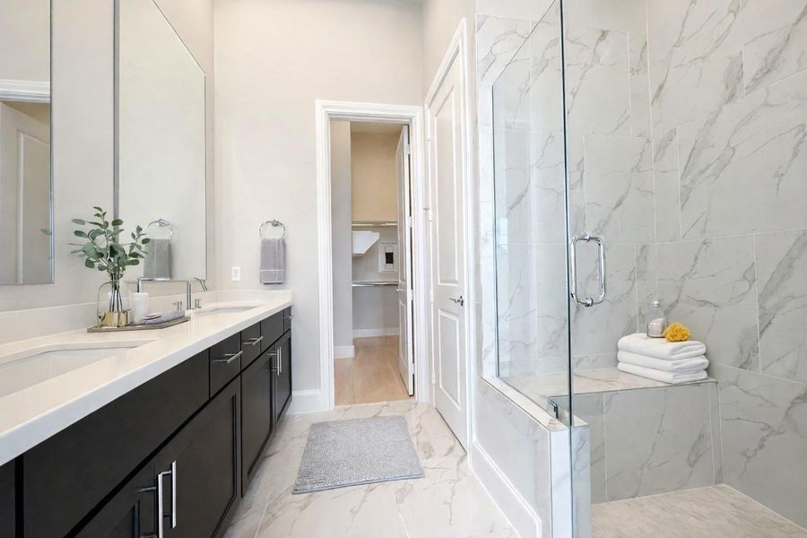 Dual vanities with separate mirrors and frameless glass shower door make this primary bathroom gorgeous.   Decor added virtually.