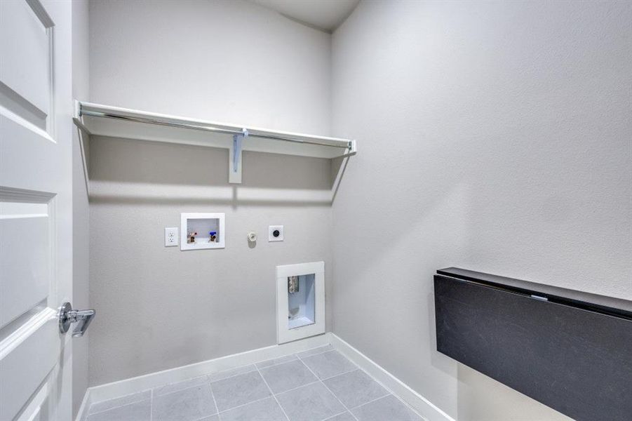 Washroom featuring light tile patterned floors, hookup for a gas dryer, hookup for an electric dryer, and hookup for a washing machine Washroom featuring light tile patterned floors, hookup for a gas dryer, hookup for an electric dryer, and hookup for a washing machine