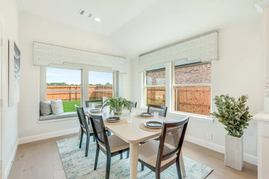 Dining room with six-chair table, window seat, and large windows overlooking backyard