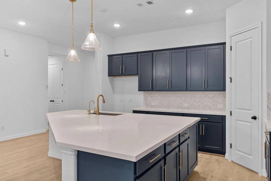 A massive island shines with beautiful white quartz countertops and a pretty gold faucet.
