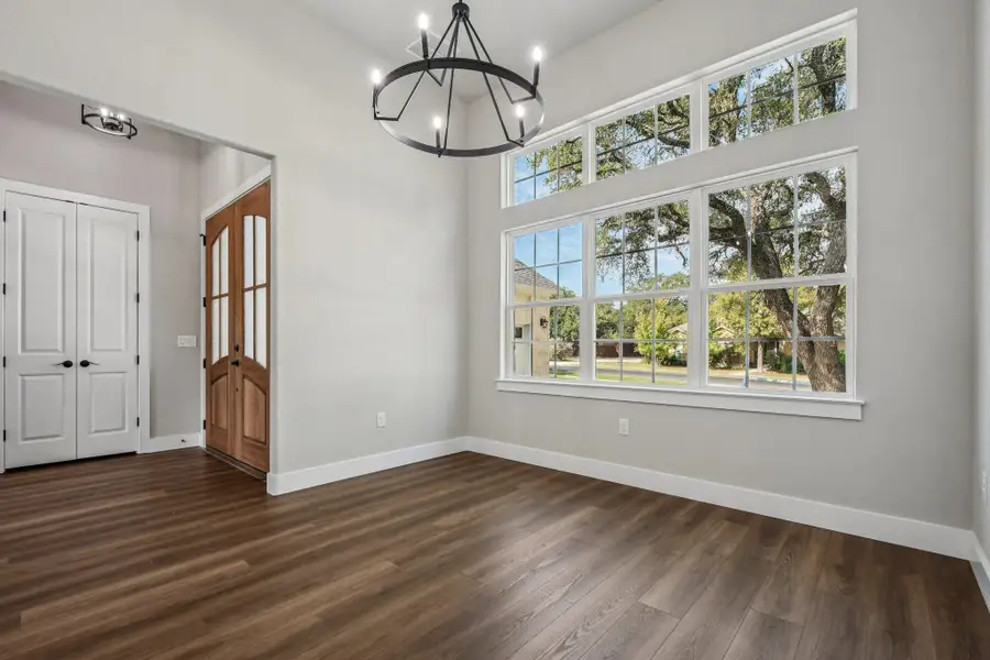 Unfurnished dining area featuring a towering ceiling, dark wood finished floors, and a chandelier