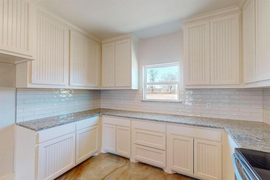 Kitchen with tasteful backsplash, light stone countertops, and stainless steel electric range