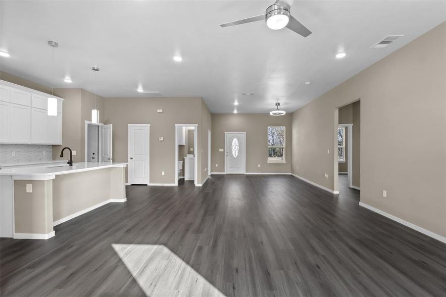 Unfurnished living room with sink, dark hardwood / wood-style floors, and ceiling fan