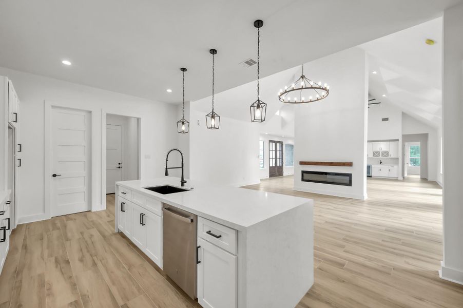 The oversized island with farmhouse-style sink and dishwasher provides both functionality and style while maintaining views into the living space.