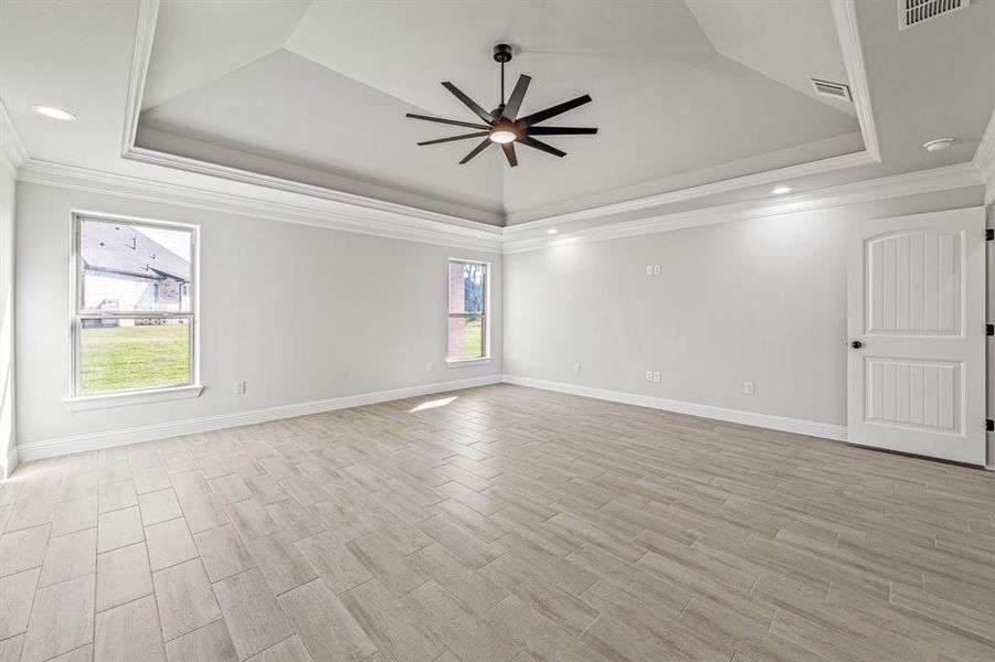 Unfurnished room featuring a raised ceiling, crown molding, wood finish floors, a ceiling fan, and recessed lighting