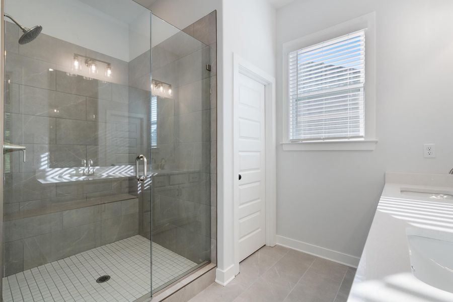 Glass-enclosed shower with a built-in bench, rainfall showerhead, and tile surround