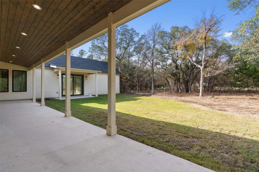 View of green lawn with a patio area View of green lawn with a patio area