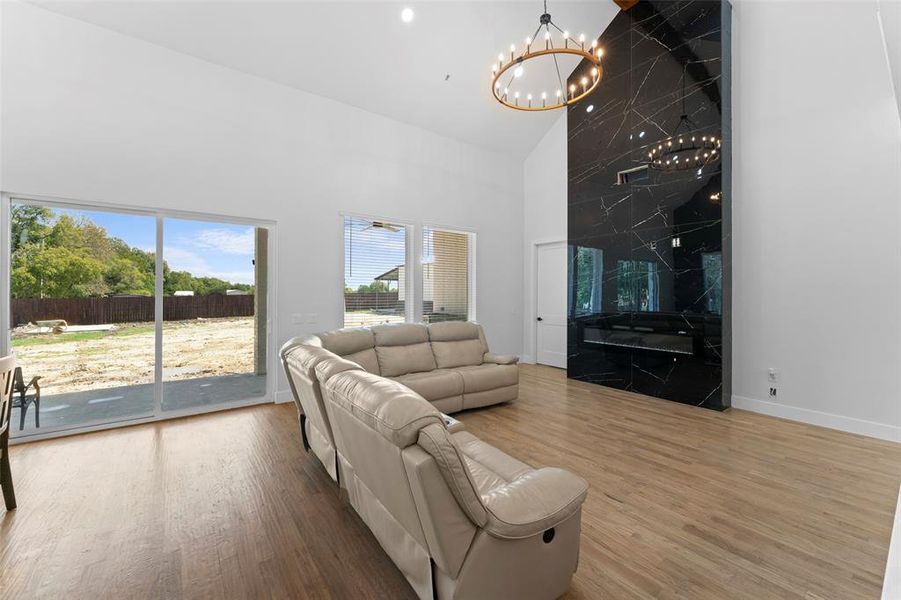 Living area featuring high vaulted ceiling, wood finished floors, and a chandelier Living area featuring high vaulted ceiling, wood finished floors, and a chandelier
