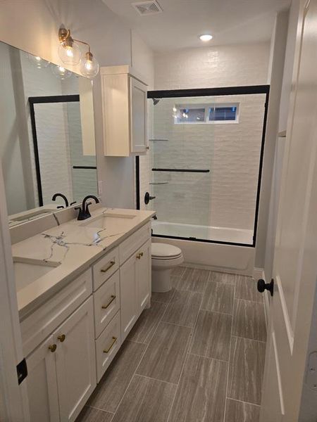 Full bathroom with vanity, toilet, and enclosed tub / shower combo