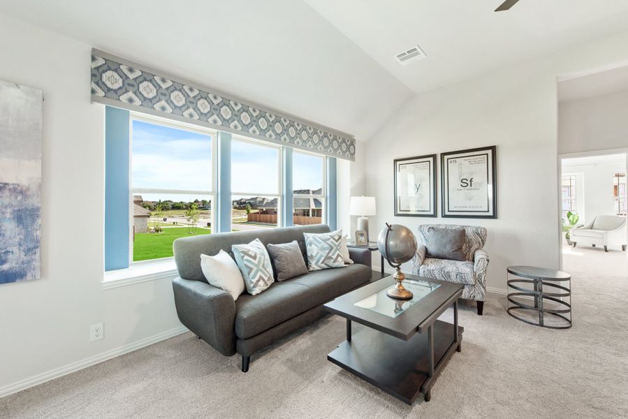 Living room with gray sofa, vaulted ceiling, and large windows overlooking a neighborhood