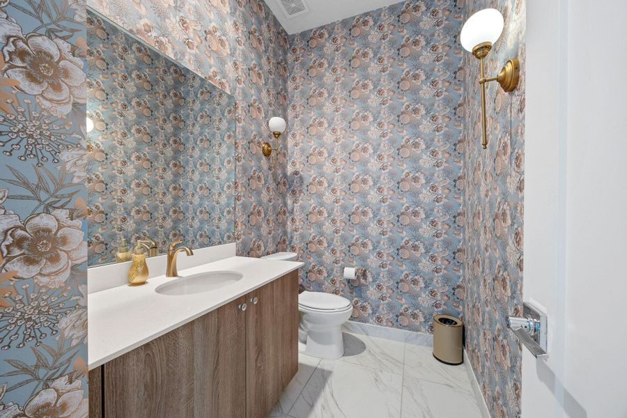 Half bath with vanity and light marble finish floors