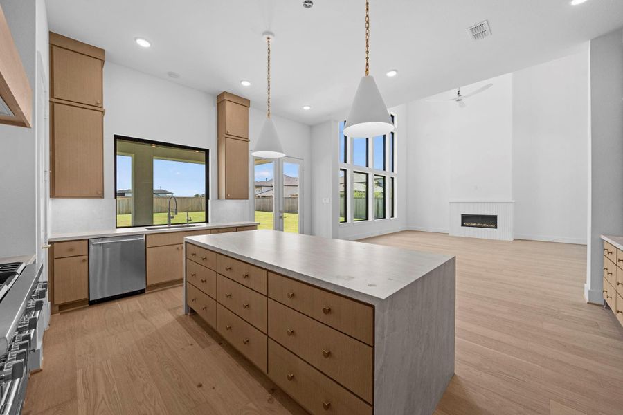 Elegant view toward the kitchen highlighting big kitchen island, tall ceilings, and open living areas.