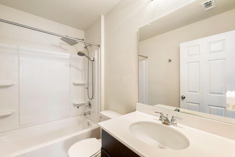 A well-appointed bathroom features a bathtub-shower combination and a clean, single vanity. A well-appointed bathroom features a bathtub-shower combination and a clean, single vanity.