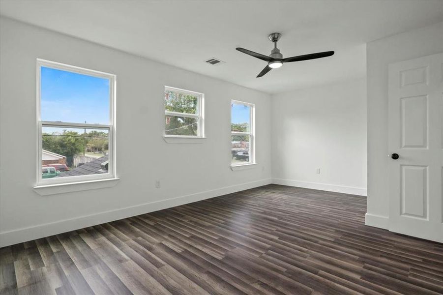 Empty room featuring dark wood-type flooring and ceiling fan