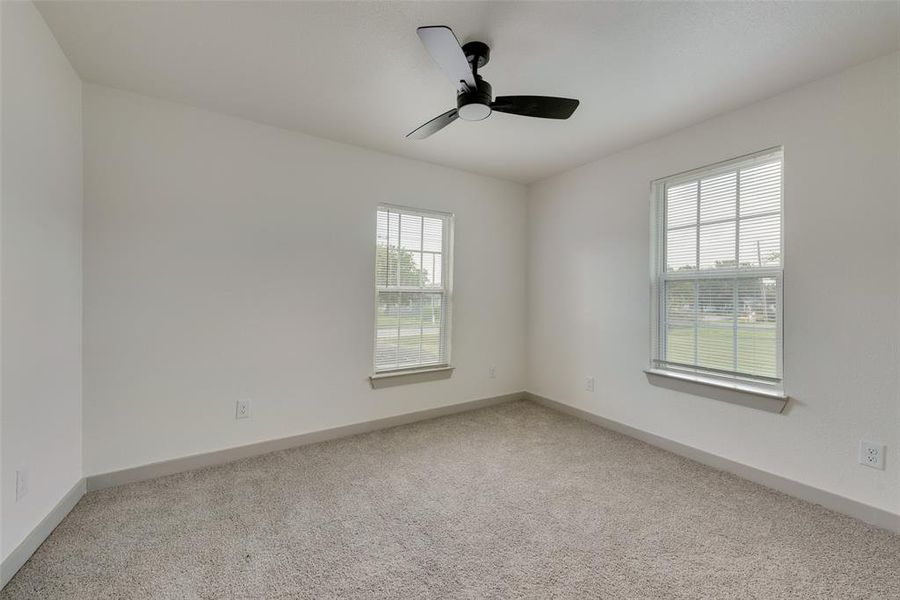 Carpeted spare room featuring plenty of natural light and ceiling fan