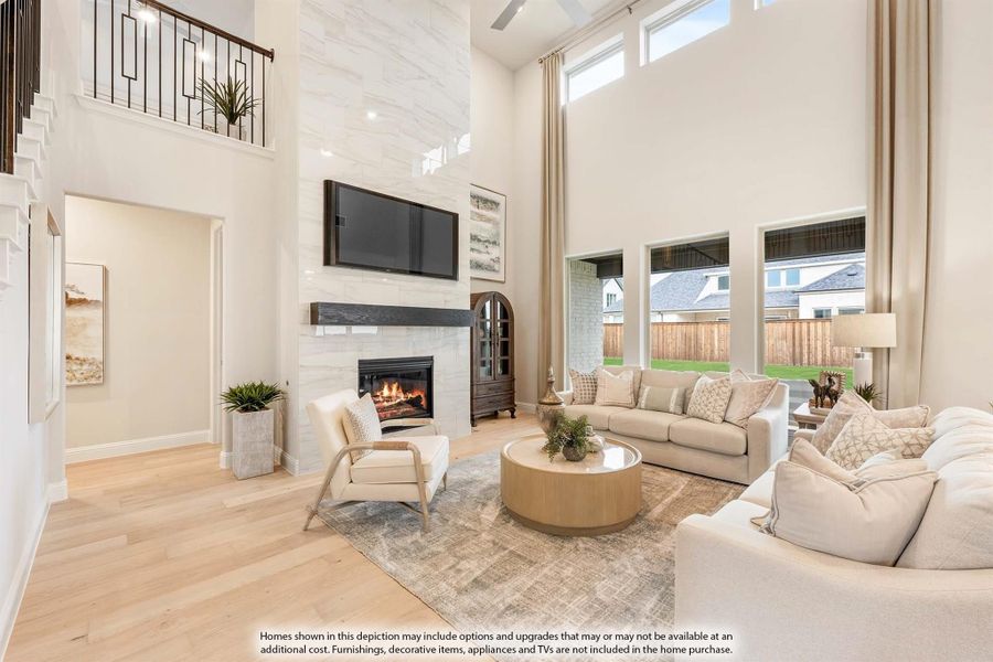 Living room with two-story ceiling, tile fireplace, wall-mounted TV, and hardwood floors
