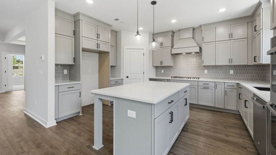 Kitchen with quartz countertops, tile backsplash, and pendant lighting