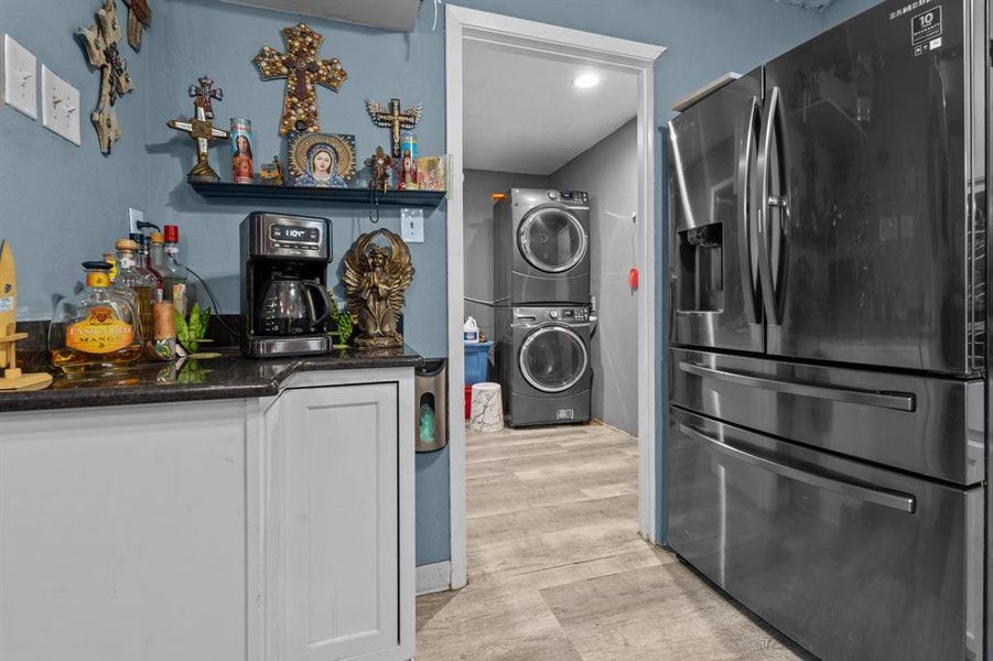 Laundry area featuring stacked washer and dryer, indoor bar, and light wood-type flooring