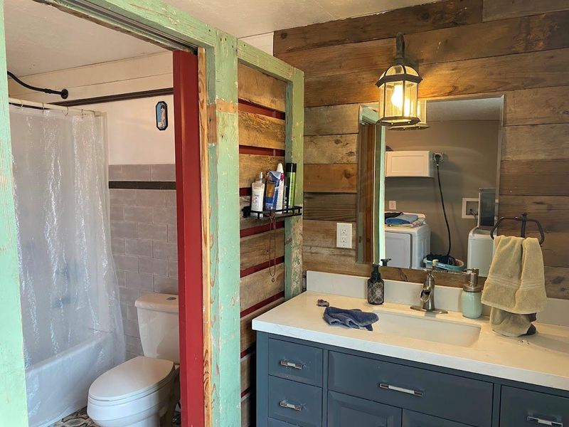 Full bathroom featuring shower / bath combination with curtain, vanity, and tile walls