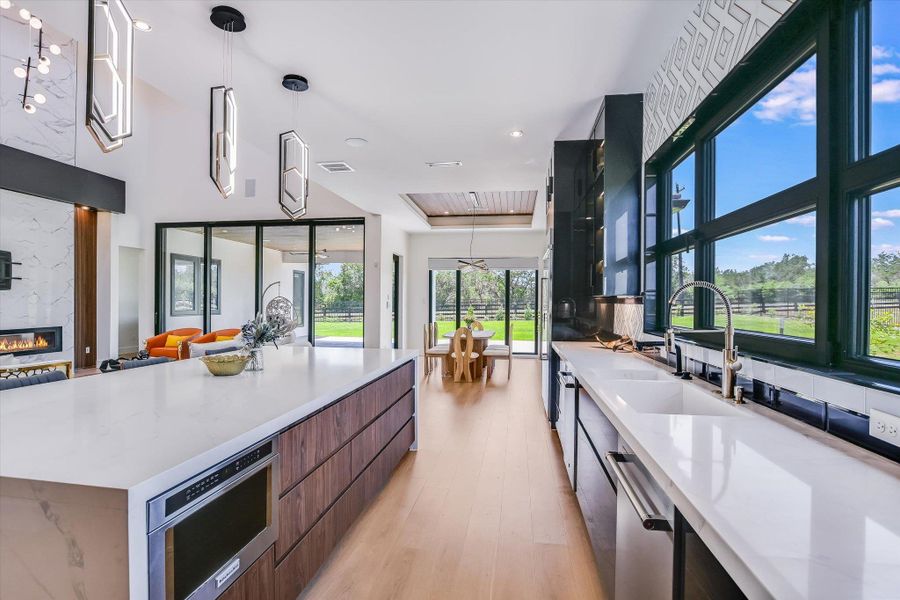 Kitchen with modern cabinets, wall of windows, dishwasher, plenty of natural light, and light wood flooring, island with microwave built in Kitchen with modern cabinets, wall of windows, dishwasher, plenty of natural light, and light wood flooring, island with microwave built in