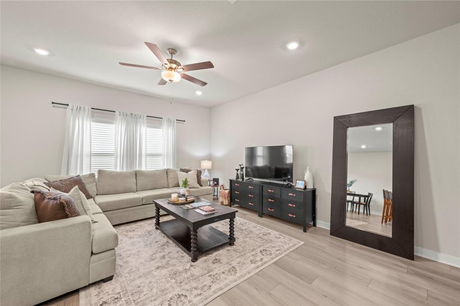 A well-lit living area showcases a comfortable seating arrangement with a subtle area rug on light hardwood flooring. A well-lit living area showcases a comfortable seating arrangement with a subtle area rug on light hardwood flooring.