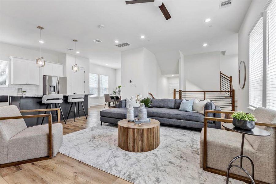 Spacious living room with a clear view of the kitchen on the left and the staircase leading up to the third floor, perfect for modern living and easy access to multiple levels.