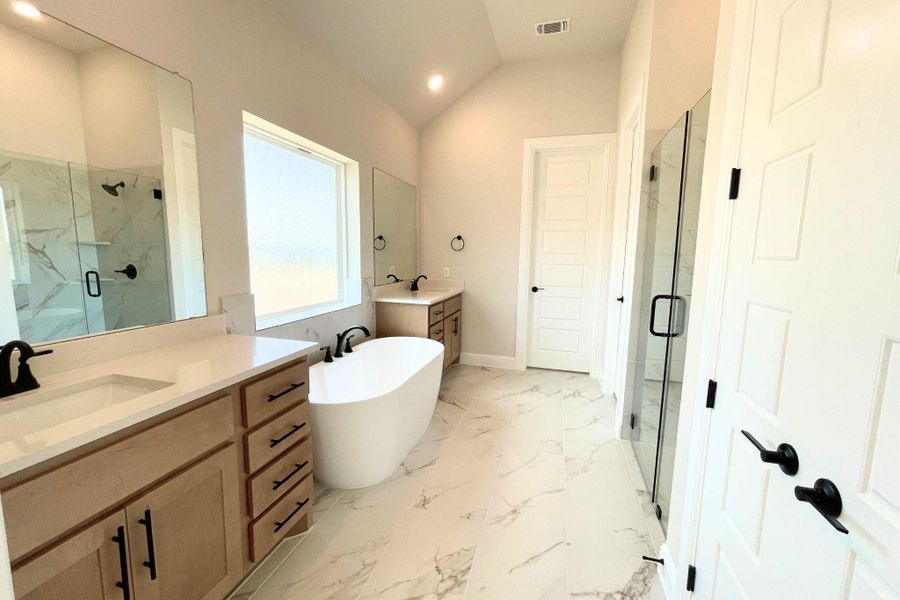 Angled ceilings and marbled tile flooring frame a freestanding tub and dual wood vanities. Angled ceilings and marbled tile flooring frame a freestanding tub and dual wood vanities.