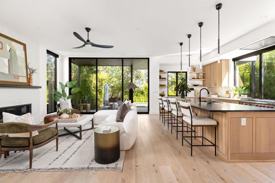 Living room with light wood-style flooring, expansive windows, a glass covered fireplace, and ceiling fan Living room with light wood-style flooring, expansive windows, a glass covered fireplace, and ceiling fan