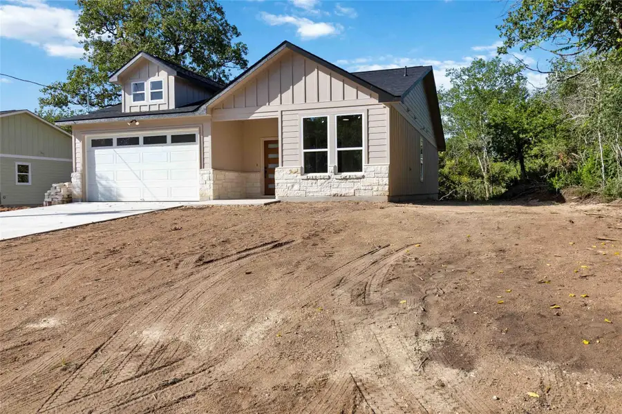 Modern farmhouse style home featuring stone siding, driveway, and board and batten siding Modern farmhouse style home featuring stone siding, driveway, and board and batten siding