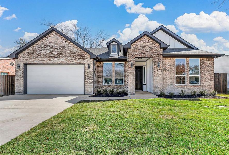 View of front of property with a front yard and a garage