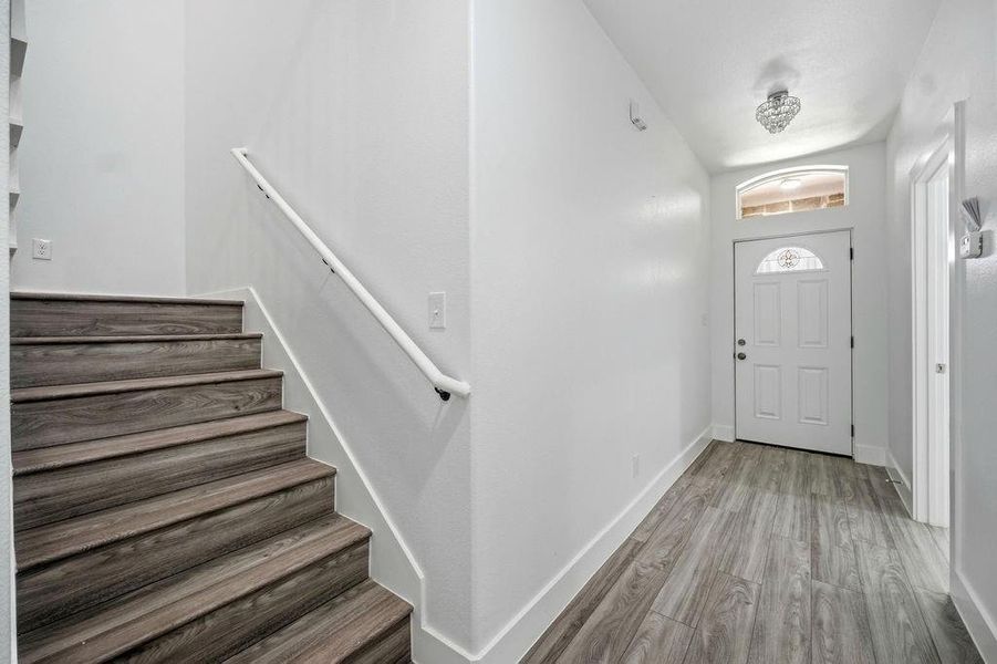 Entryway with wood-finish flooring, a white paneled door featuring decorative glass, and an arched transom window Entryway with wood-finish flooring, a white paneled door featuring decorative glass, and an arched transom window