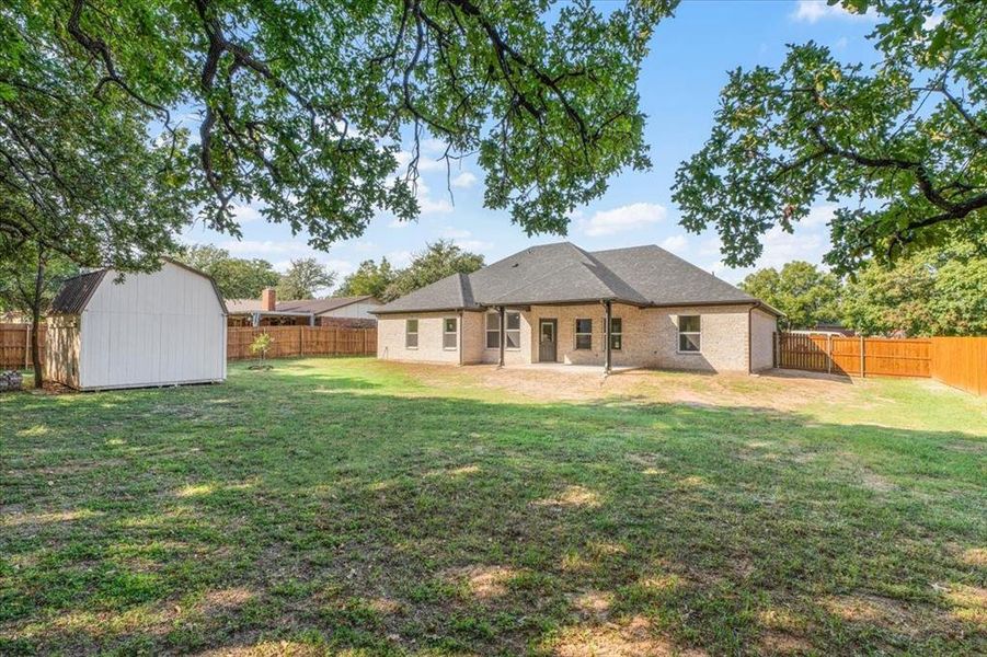 Back of property with a storage unit and a yard